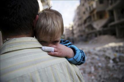 رجل يحمل ابنه في حي دوما في دمشق الذي تعرض للقصف أمس (رويترز) 