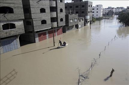 عنصر من الدفاع المدني الفلسطيني يستخدم زورقا لانقاذ اخرين في شوارع مغمورة بالمياه جراء العاصفة في غزة امس (ا ب)