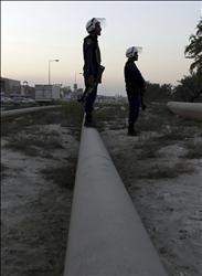 شرطيان بحرينيان يقفان عند خط إمداد للنفط يصل إلى السعودية لمراقبة متظاهرين معارضين للحكومة في قرية بوري، أمس. 