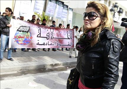 تونسية تمرّ بالقرب من تظاهرة لحزب «التحرير» الإسلامي أمام السفارة الفرنسية في تونس، أمس (رويترز) 