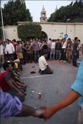 اقباط يحمون مسلمين يصلون بعد مشاركتهم في تشييع القتلى داخل الكاتدرائية المرقسية في حي العباسية في القاهرة امس (رويترز) 