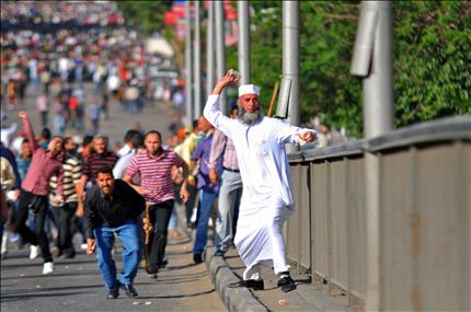 احد انصار «الاخوان» يرشق الحجارة باتجاه متظاهرين معارضين خلال الاشتباكات في وسط القاهرة أمس (أ ب) 