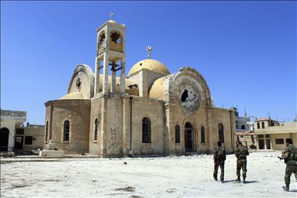 جنود سوريون امام كنيسة متضررة جراء الاشتباكات مع المسلحين في القصير امس الاول (رويترز) 