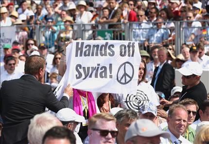 عنصرا أمن يحاولان انتزاع لافتة من محتجة كتب عليها «ارفعوا أيديكم عن سوريا» خلال إلقاء أوباما خطابا أمام بوابة «براندبورغ» في برلين امس (ا ف ب) 