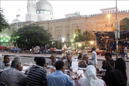 مصريون يتناولون الإفطار على طاولة لـ«موائد الرحمن» في القاهرة أمس (رويترز) 