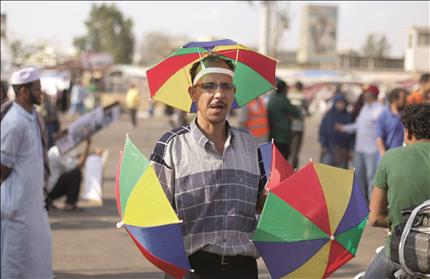 بائع مظلات مصري في تقاطع «رابعة العدوية» في القاهرة أمس (أ ب) 