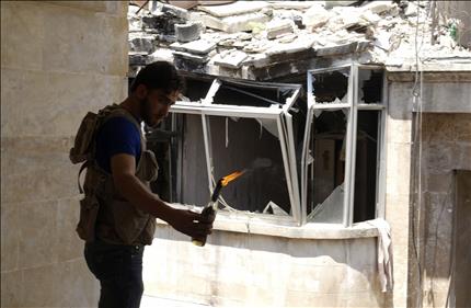 مسلح يرمي قنبلة مولوتوف خلال اشتباكات مع القوات السورية في حي صلاح الدين في حلب امس (رويترز) 