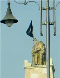 علم تنظيم "داعش" فوق تمثال "الحرية" الذي يجسد فلاحا وفلاحة بالزي التقليدي يرفعان مشعلا بعد قطع رأسيهما في الرقة امس (ا ف ب) 