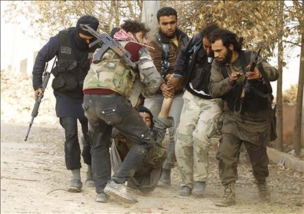 مسلحون ينقلون زميلا لهم اصيب خلال الاشتباكات مع القوات السورية قرب مقر «اللواء 80» في حلب امس (رويترز) 