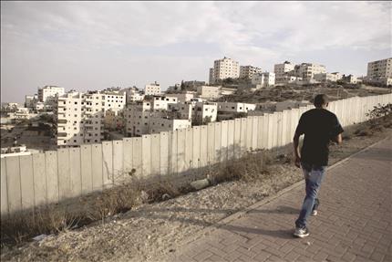 فلسطيني يمر أمام جدار الفصل العنصري في مخيم شعفاط في شمال القدس المحتلة أمس (ا ب ا) 