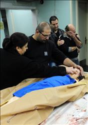 أقارب أحد الأطفال الذين استشهدوا في دمشق أمس الأول يبكون حول جثته في مستشفى في دمشق أمس (أ ف ب) 