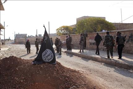 جنود سوريون يمرون قرب علم «جبهة النصرة» في تل حاصل في محافظة حلب أمس (رويترز) 