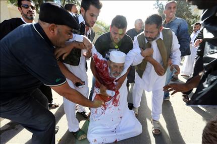 ليبيون يساعدون أحد المصابين بعدما فتح عناصر «ميليشيا مصراتة» النار على المحتجين السلميين في جنوب العاصمة طرابلس أمس (أ ف ب) 