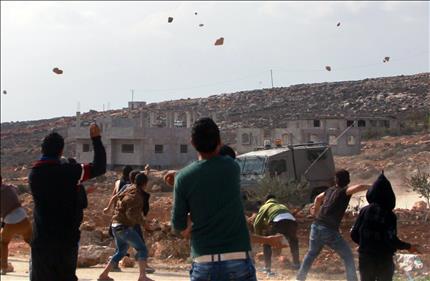 فلسطينيون يرشقون قوات الاحتلال بالحجارة في قرية قصرة في جنوب شرقي نابلس أمس، وذلك بعدما حاول مستوطنون الاعتداء على حقول زيتون في المنطقة (أ ف ب) 