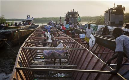 نازحون ينقلون ممتلكاتهم من المراكب التي استخدموها للهرب من بور في مدينة أويريال في وسط جنوب السودان (أ ب) 