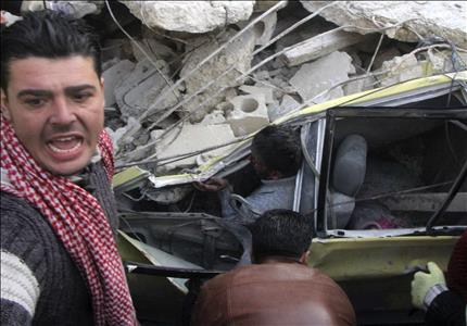 سوريون يحاولون مساعدة شخص علق داخل سيارته جراء غارة جوية في حلب امس (رويترز)