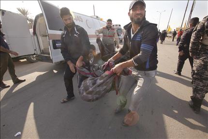 عراقيان يحملان جثة رجل قتل في التفجير الانتحاري في الدورة امس (ا ف ب)