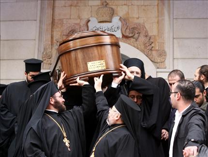 كهنة يحملون جثمان هزيم امام مدخل الكاتدرائية المريمية في دمشق امس (ا ف ب) 
