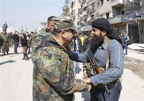 مسلح يتحدث مع جندي سوري في ببيلا في ريف دمشق امس بعد اتمام المصالحة فيها (رويترز)