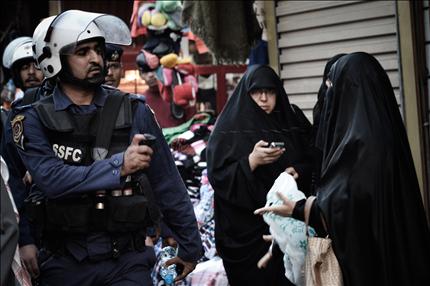 شرطي بحريني يرش رذاذ فلفل على إحدى المتظاهرات في السوق القديم في المنامة، أمس (أ ف ب) 
