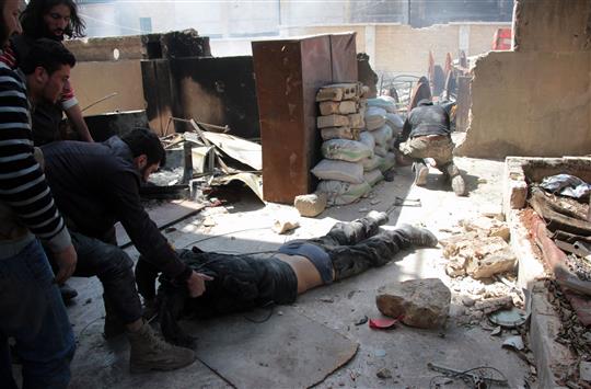 مسلح يجر جثة زميله الذي قتل بنيران القوات السورية في حلب امس (ا ف ب)