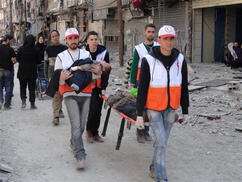 عناصر من «الهلال الأحمر» السوري يجلون مدنيين من اليرموك الشهر الماضي (أ ب أ)