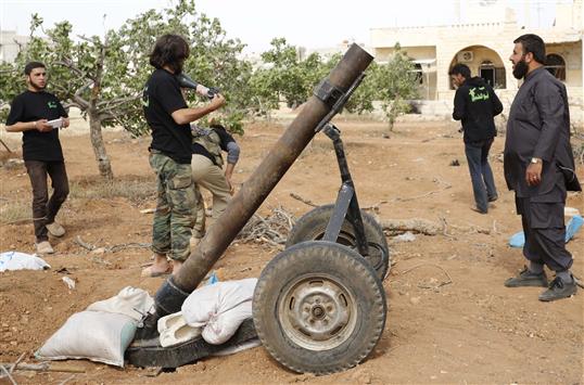 مسلحون يستعدون لاستهداف القوات السورية في قرية مورك في ريف حماه امس الاول (رويترز)