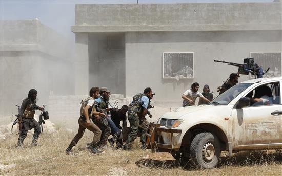 مسلحون ينقلون زميلا لهم اصيب في اشتباك مع القوات السورية في قرية مورك في ريف حماه امس (رويترز)