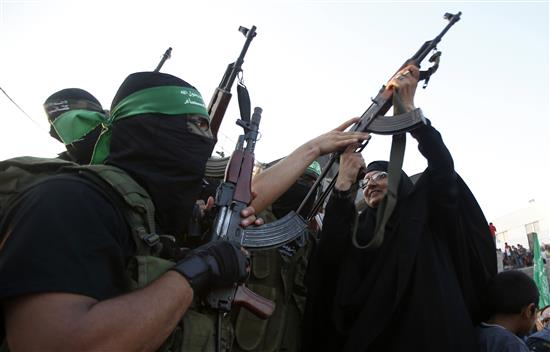امرأة فلسطينية تمسك بسلاح مقاوم احتفالاً بالانتصار في غزة أمس (رويترز)