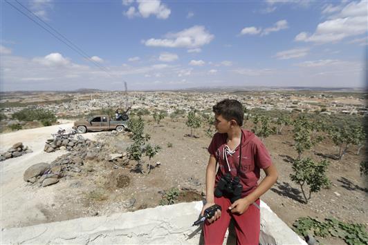 مراهق يحمل جهازاً ومنظارا للإبلاغ عن تحركات القوات السورية في جبل الزاوية في ريف ادلب أمس الاول (رويترز)