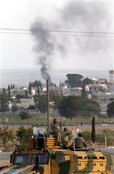 جنود اتراك فوق آلية عسكرية وفي الخلف دخان يتصاعد من عين العرب امس (ا ب ا)