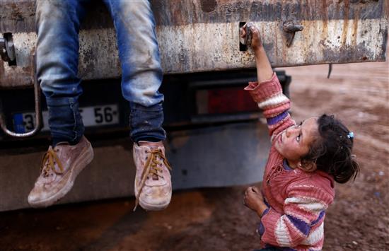 طفلة سورية تحاول تسلق شاحنة لنقلها مع لاجئين اخرين فروا من عين العرب الى مخيم داخل تركيا امس (ا ب ا)