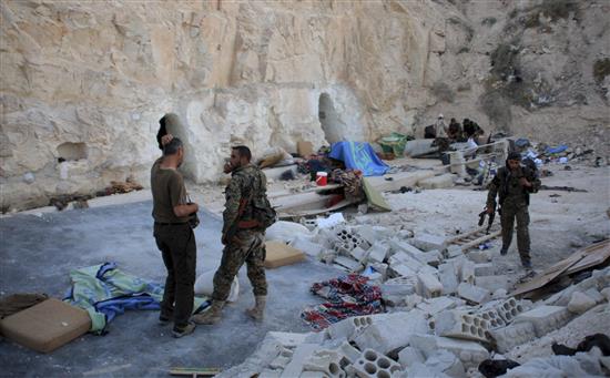 جنود من الجيش السوري يعاينون موقعاً كان يختبئ فيه مسلحون في حماه أمس الأول (رويترز)