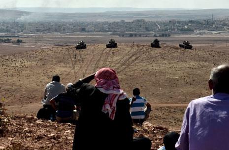 يتابعون المعارك في عين العرب وأمامهم دبابات تركية على الحدود أول من أمس (أ ف ب)