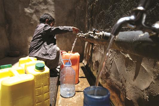 طفل يملأ غالونات مياه في صنعاء، أمس (رويترز)
