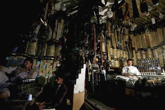 يمني يجلس في متجره من دون كهرباء في الناحية القديمة من صنعاء، أمس (رويترز)