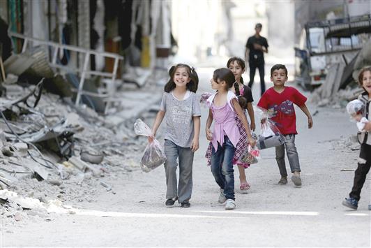 اطفال يحملون ثيابا جديدة في جوبر في ريف دمشق امس الاول (رويترز)