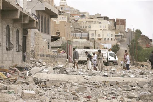 أشخاص يجمعون ما تبقّى من ممتلكات منزلهم الذي دمره القصف في صنعاء، أمس (رويترز)