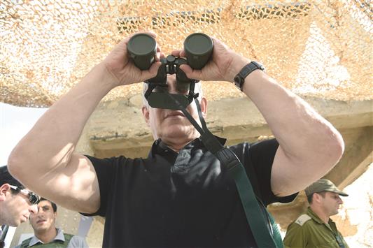 نتنياهو ينظر من خلال منظار مغلق، خلال زيارته قاعدة عسكرية على مشارف قطاع غزة، أمس (أ ف ب)
