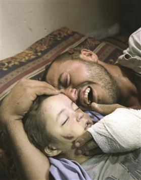 الفلسطيني يحيى حسان ينتحب فوق جثمان طفلته رهف (عامان) التي استشهدت وامّها الحامل، في مخيم النصيرات في غزة، امس (ا ف ب)