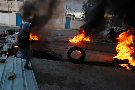 فتى فلسطيني يشعل الإطارات خلال مواجهات مع الاحتلال في مخيم الجلزون شمال رام الله (أ ف ب)