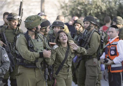 جندية اسرائيلية تنتحب في موقع طعن في الضفة الغربية أمس (رويترز)