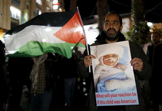 فلسطيني يحمل صورة طفل مصاب خلال تظاهرة ضد كيري في رام الله أمس (رويترز)