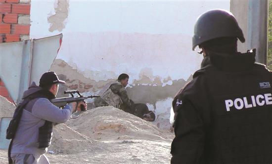 عنصر في القوات الأمنية التونسية يتفقد جثة مسلح خلال الاشتباكات في بن قردان قرب الحدود الليبية أمس (ا ف ب)