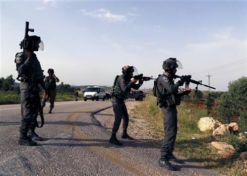 جنود الاحتلال يوجهون اسلحتهم باتجاه متظاهرين فلسطينيين قرب نابلس امس (رويترز)