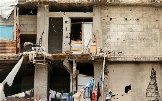 فلسطينيتان تنظران امس من منزلهما الذي دمر في العدوان الاسرائيلي على غزة في العام 2014 (رويترز)