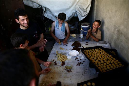 سوريون يصنعون حلوى العيد في دوما في الغوطة الشرقية أمس الأول (رويترز)