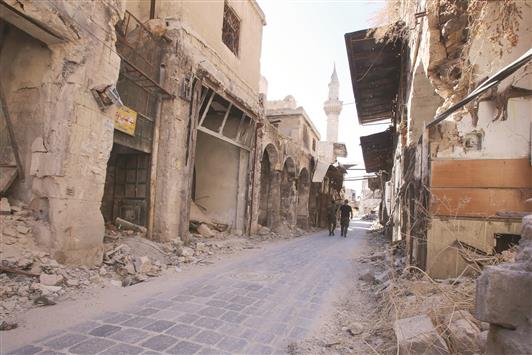 جنديان سوريان يسيران في سوق الفرافرة في مدينة حلب القديمة أمس (أ ف ب)