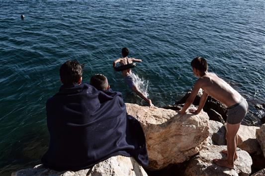 لاجئون يسبحون في مياه جزيرة كيوس اليونانية (أ ف ب)