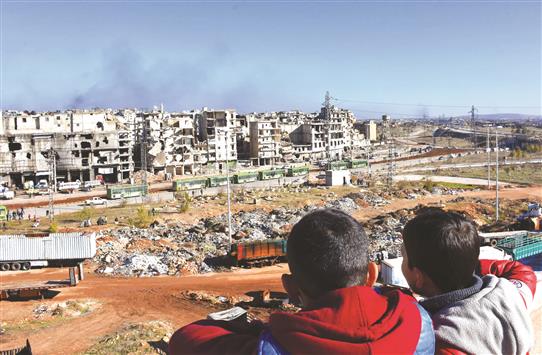 طفلان سوريان يراقبان عملية إجلاء المسلحين وعائلاتهم من الاحياء الشرقية لحلب أمس (أ ف ب)